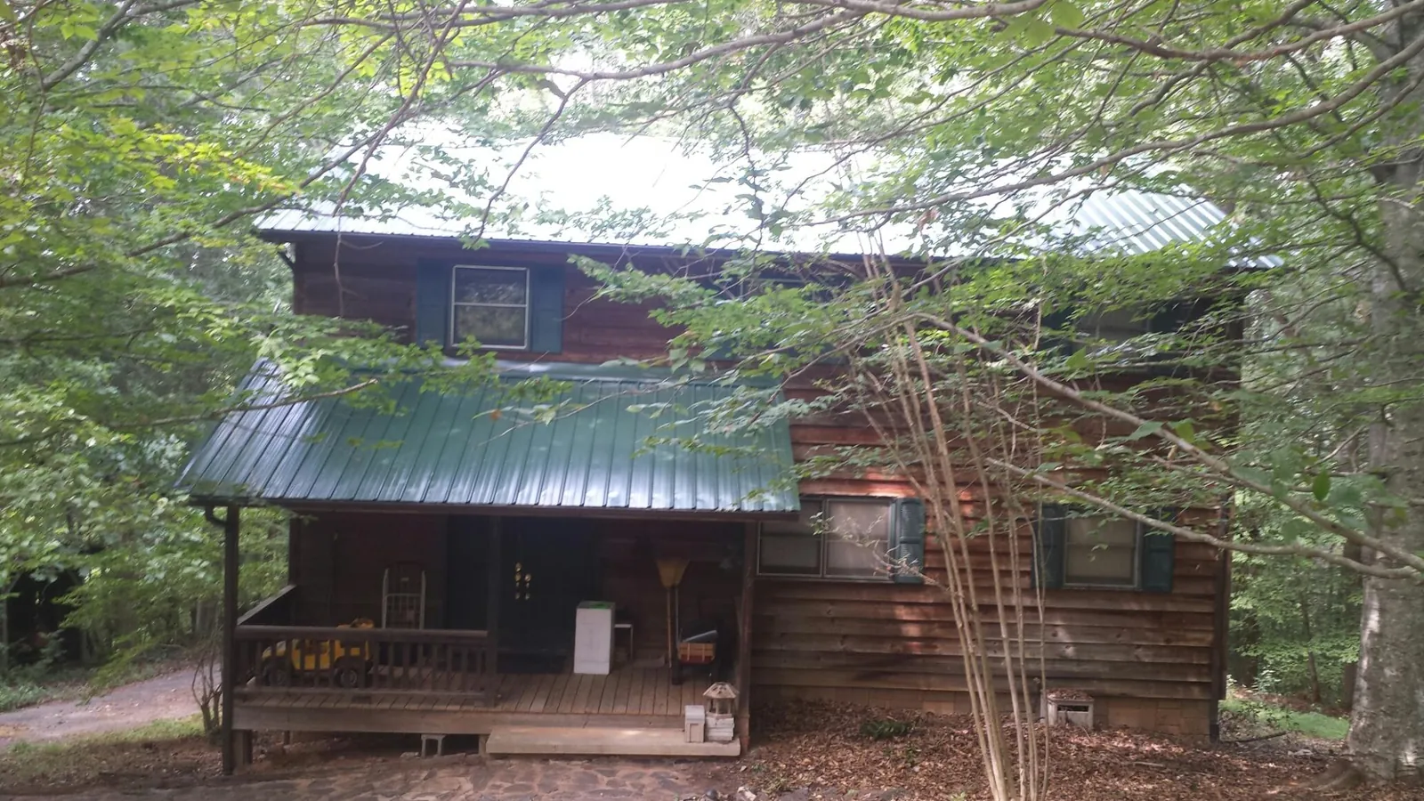 Green metal roof and covered porch on a log cabin in Portland