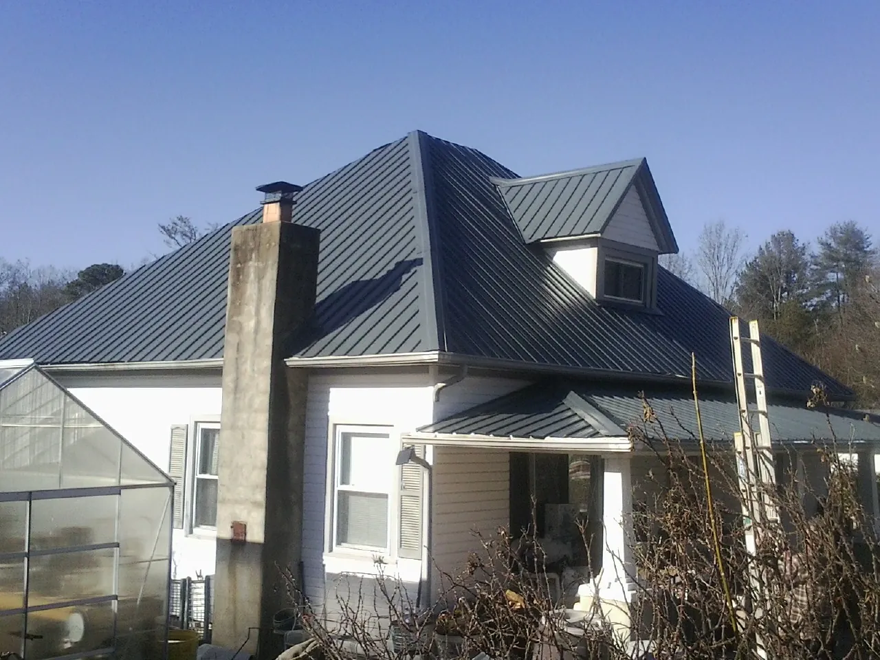 Dark blue standing seam metal roof on a white farmhouse with dormer — Slate & Tile Roof Repair by Roofing Brothers in Portland