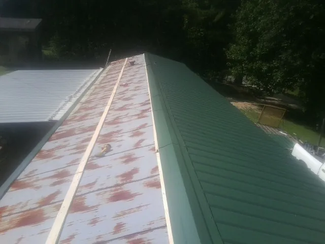 Old rusted panels beside newly installed green metal roofing — Wind Damage Roof Repair by Roofing Brothers in Portland