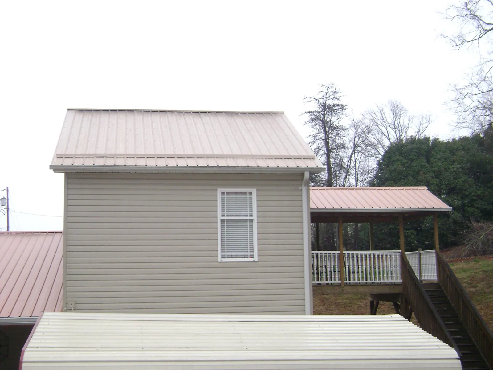 Tan metal roofs on a two story addition and attached porch, from a Roof Replacement job in Portland